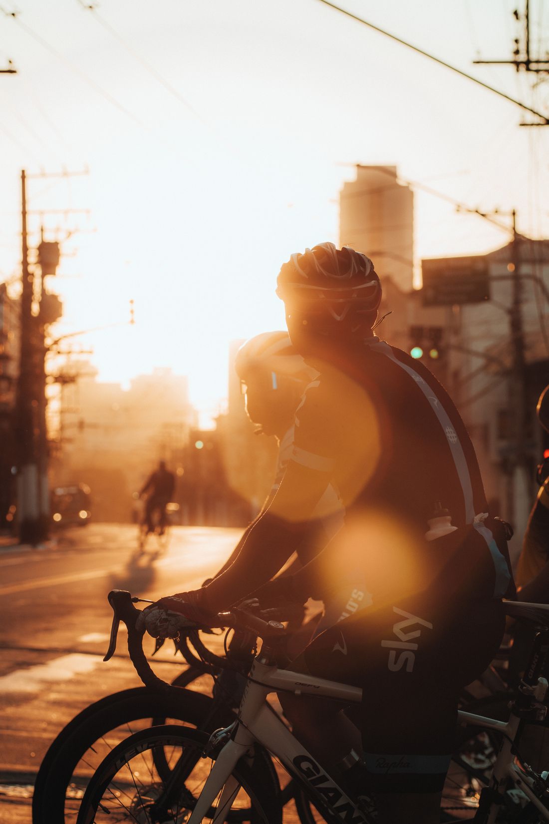 Cyclist riding through city streets illuminated by golden sunrise