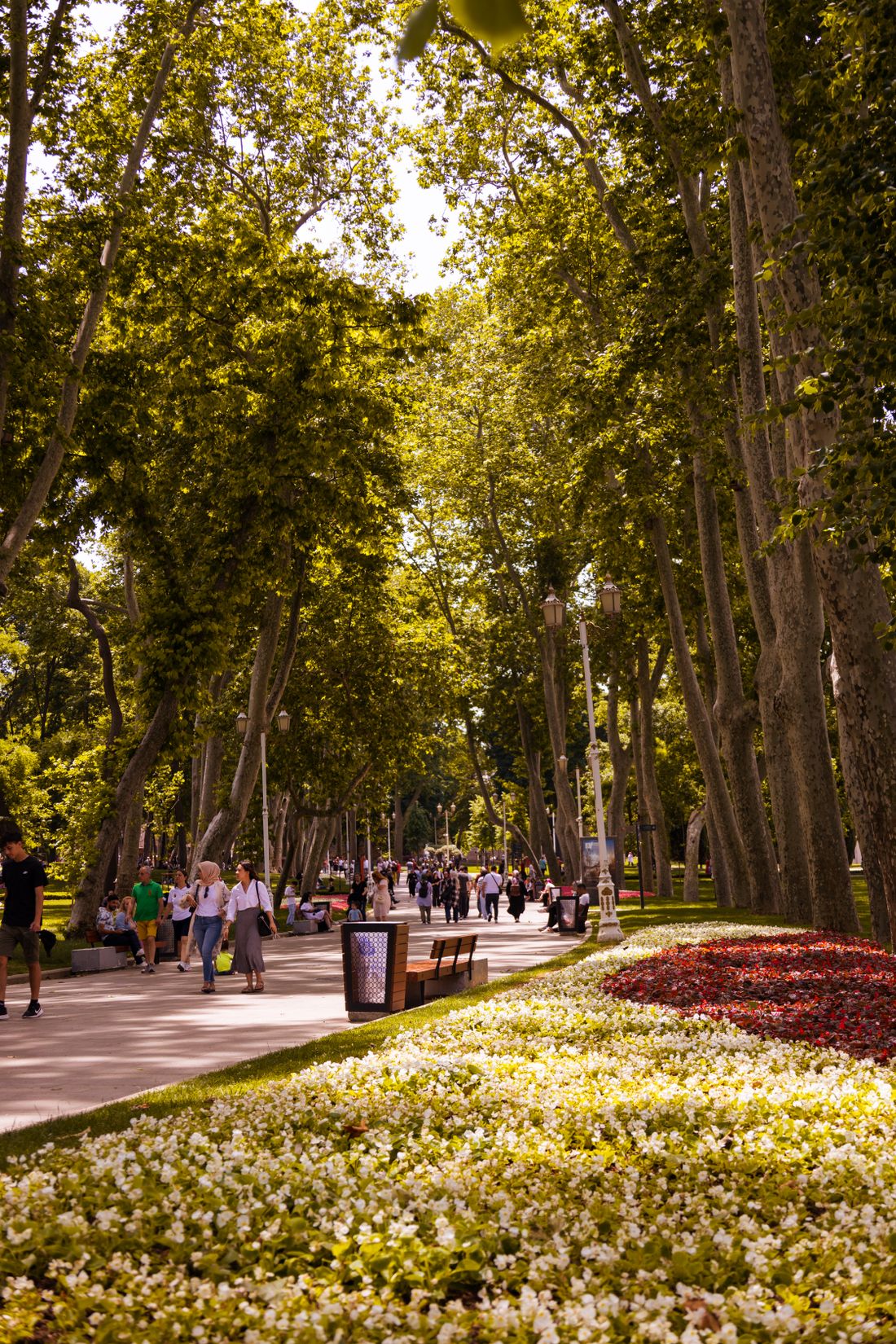 People walking through a city park along flowerbeds